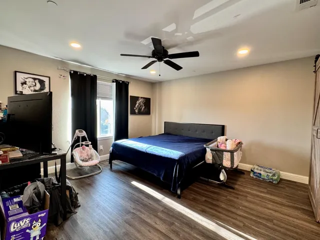 a living room with furniture a ceiling fan and a flat screen tv