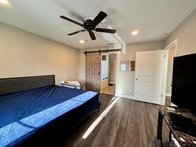 a spacious bedroom with a bed and a flat screen tv