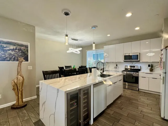 a large white kitchen with kitchen island a sink a stove and a refrigerator