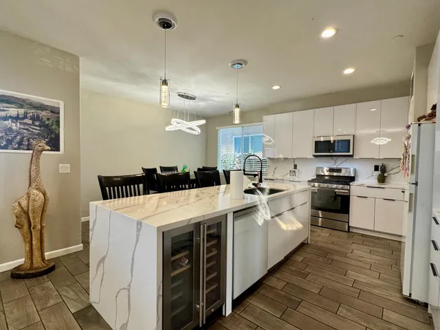 a large white kitchen with kitchen island a sink a stove a microwave and a refrigerator