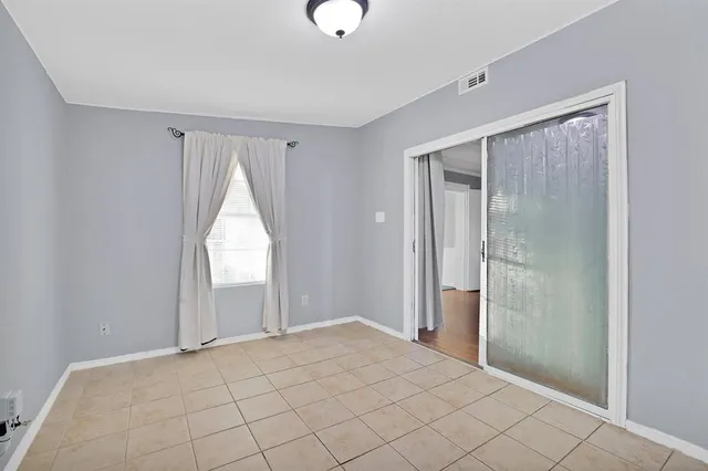 a view of an empty room with window and chandelier fan