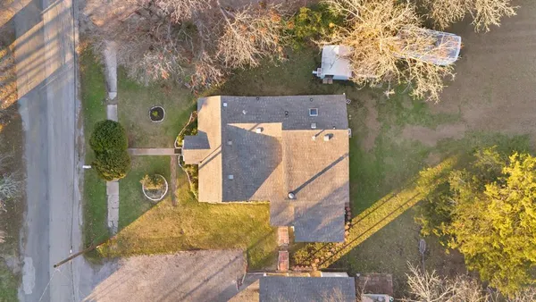 aerial view of a house with a yard and large trees