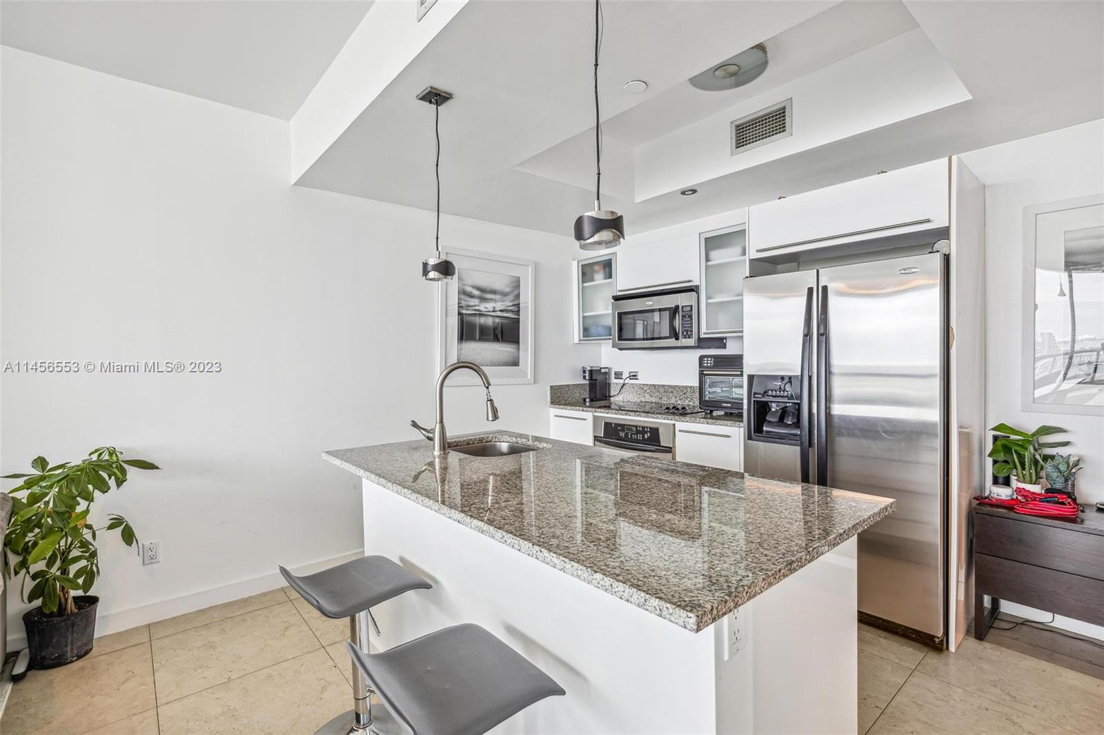 888 Biscayne Boulevard, Unit 1809 Miami, FL 33132 - Photo 12 of 37 a kitchen with granite countertop a sink a counter top space appliances and cabinets