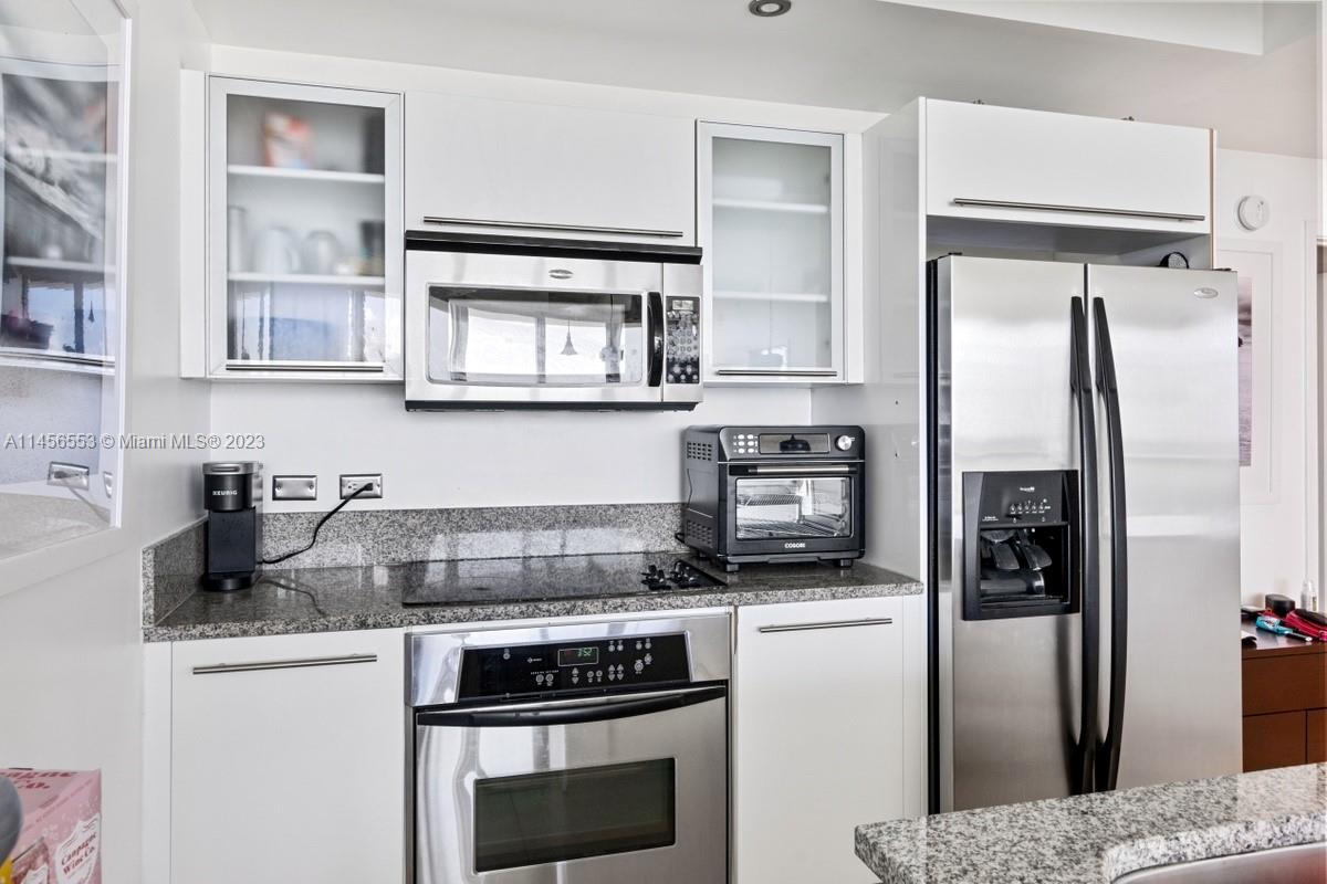 888 Biscayne Boulevard, Unit 1809 Miami, FL 33132 - Photo 13 of 37 a kitchen with stainless steel appliances granite countertop a refrigerator a stove and a sink with wooden floor
