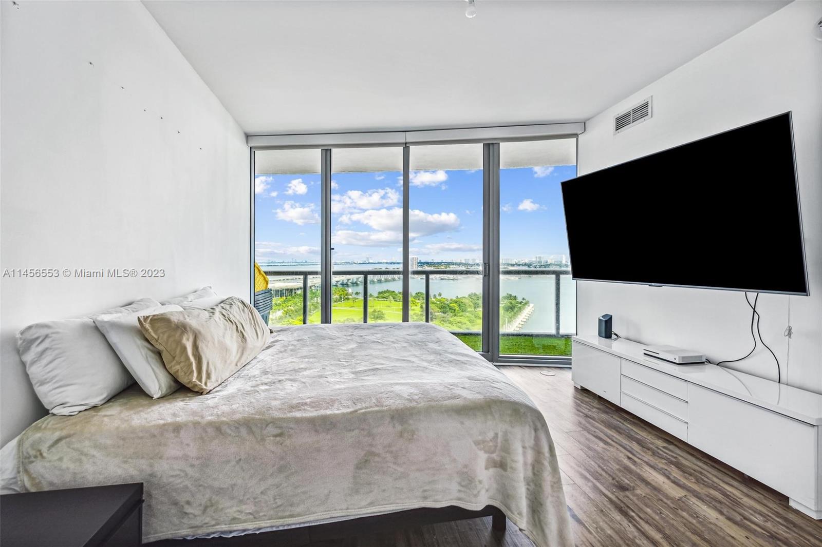 888 Biscayne Boulevard, Unit 1809 Miami, FL 33132 - Photo 15 of 37 a bedroom with a bed tv and a large window
