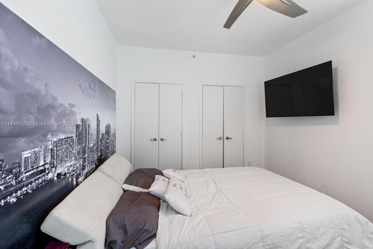 888 Biscayne Boulevard, Unit 1809 Miami, FL 33132 - Photo 20 of 37 a bedroom with a bed a flat screen tv and guitar