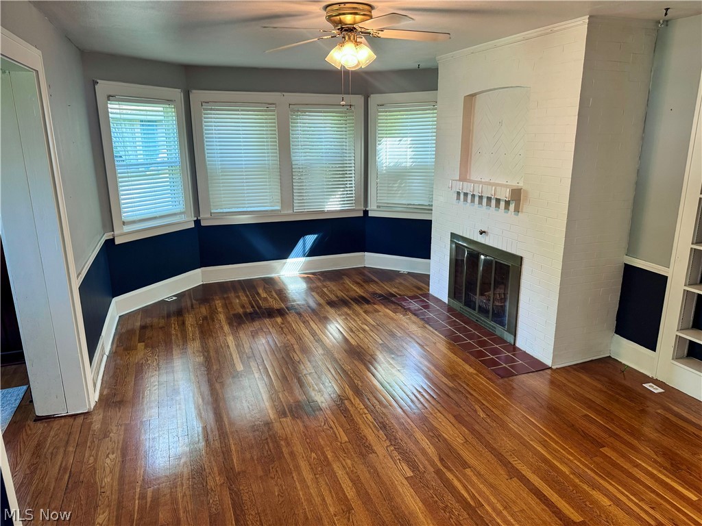 7121 North Lima Road Youngstown, OH 44514 - Photo 12 of 37 Hardwood flooring throughout featuring a brick fireplace with a tile hearth and a bay window with multiple panes