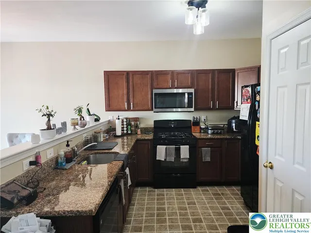 a kitchen with granite countertop a stove a sink and a microwave