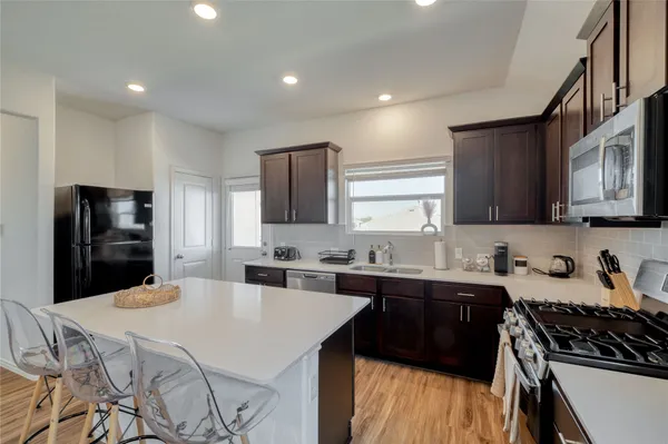 a kitchen with stainless steel appliances a sink a stove a refrigerator cabinets and a counter top space