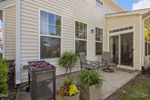 a view of a house with potted plants and a table and chairs