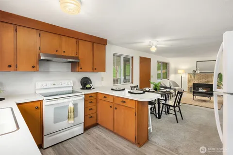 a view of a kitchen counter space with stainless steel appliances granite countertop wooden cabinets a dining table and chairs