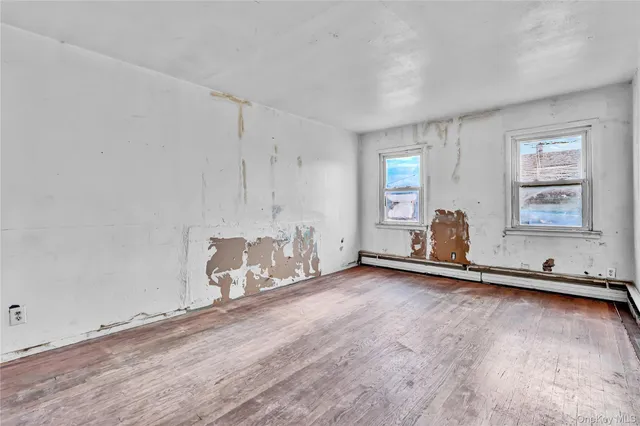 an empty room with chandelier fan and windows