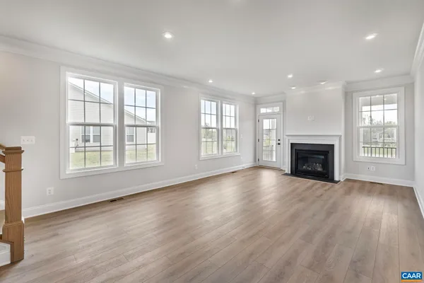 a view of an empty room with wooden floor fireplace and a window