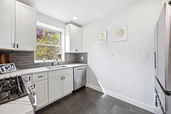 a kitchen with white cabinets and window
