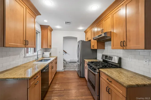 a kitchen with stainless steel appliances granite countertop a stove a sink and a refrigerator