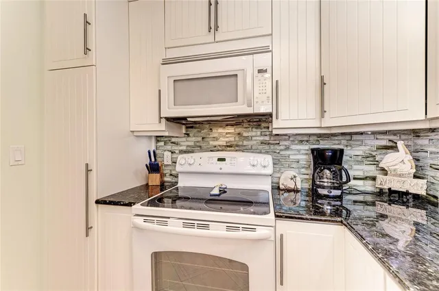 a kitchen with a stove and white cabinets