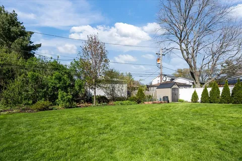 a view of a house with a big yard and large trees