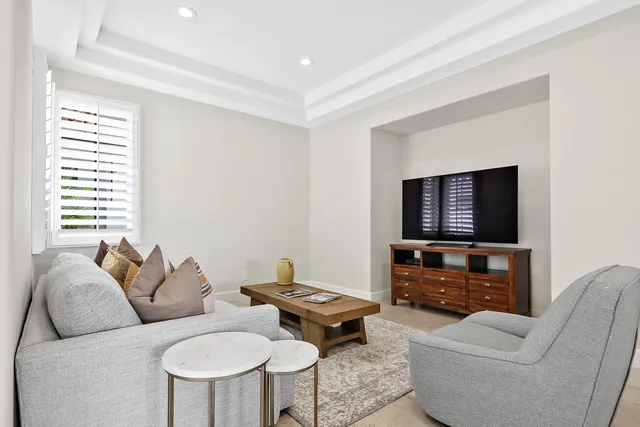 a living room with furniture a flat screen tv and a window