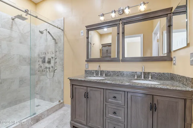 a bathroom with a granite countertop sink a mirror a shower and a bathtub