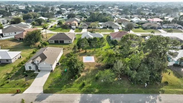 an aerial view of residential houses with outdoor space and trees