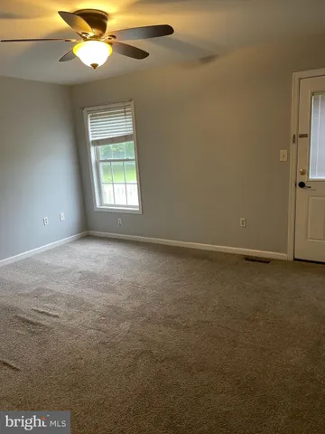 an empty room with a window and a fan