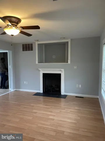 a view of an empty room with wooden floor and a fireplace