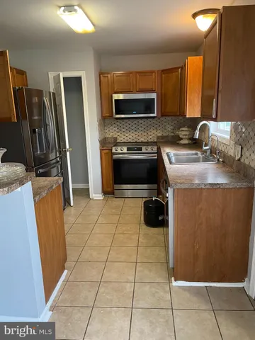 a kitchen with stainless steel appliances a stove a microwave a sink a refrigerator and a counter