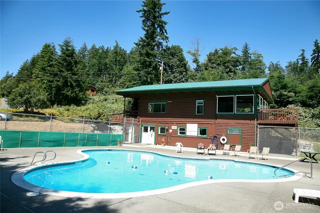 a view of house with swimming pool and a yard