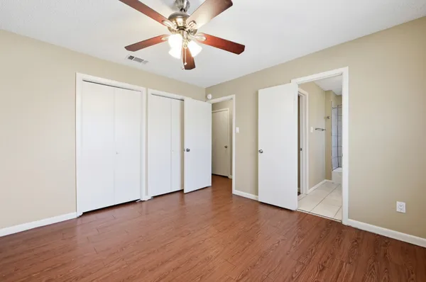 an empty room with wooden floor chandelier fan and closet area