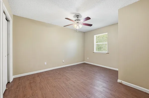 an empty room with a window and a fan