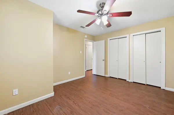 an empty room with wooden floor a ceiling fan and closet