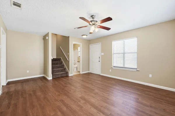 a view of an empty room with wooden floor and a window