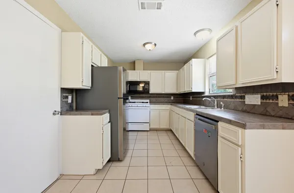 a kitchen with stainless steel appliances granite countertop a stove a sink and white cabinets