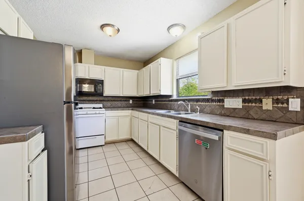 a kitchen with cabinets appliances a sink and a window