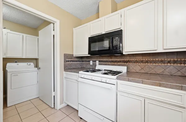 a kitchen with white cabinets and appliances