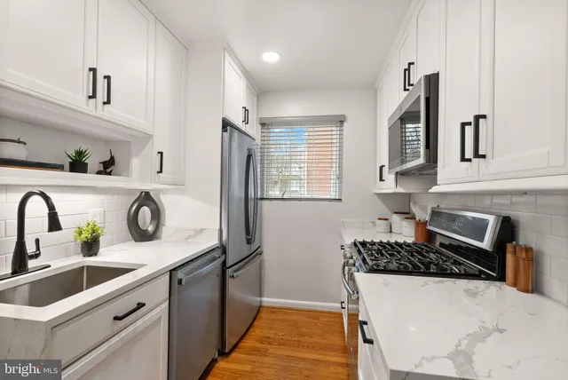 a kitchen with stainless steel appliances white cabinets and stove top oven