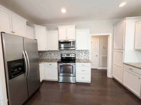 a kitchen with stainless steel appliances a refrigerator a stove and white cabinets