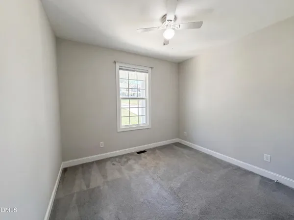 an empty room with a window and a fan