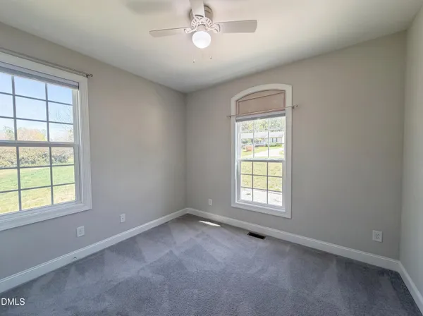 an empty room with a window and a fan