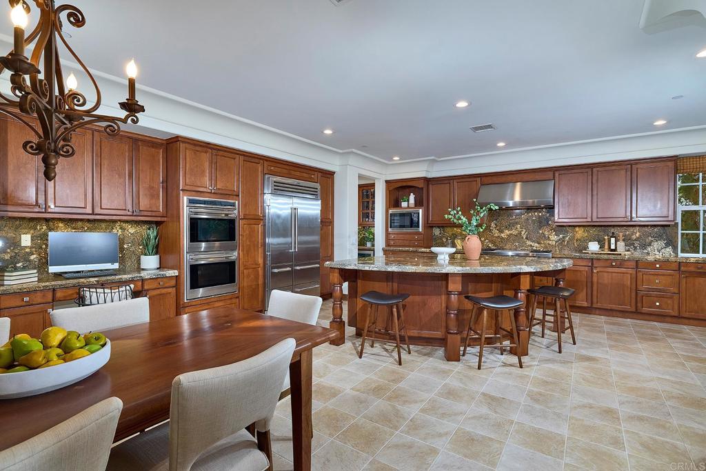 6591 Halite Place Carlsbad, CA 92009 - Photo 9 of 33 a kitchen with stainless steel appliances kitchen island granite countertop a table chairs and a refrigerator