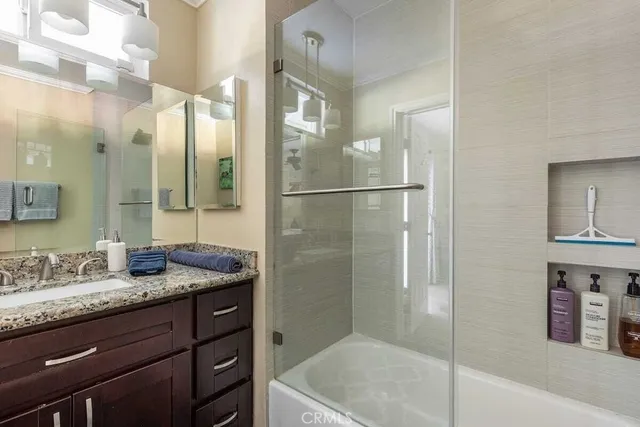 a bathroom with a granite countertop sink a mirror and a shower