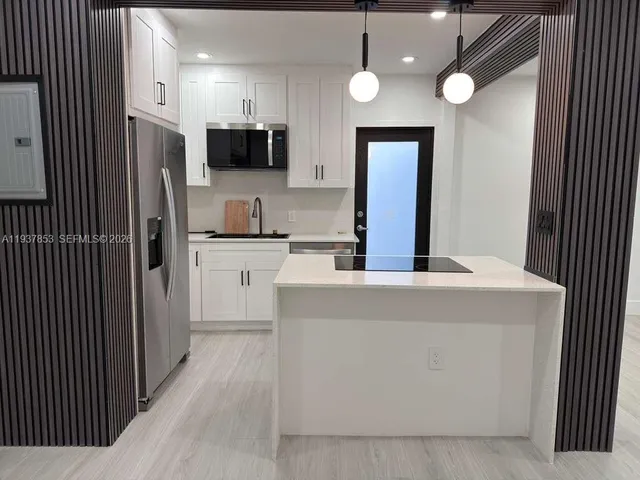 a view of kitchen with stainless steel appliances granite countertop refrigerator oven a sink dishwasher and white cabinets with wooden floor