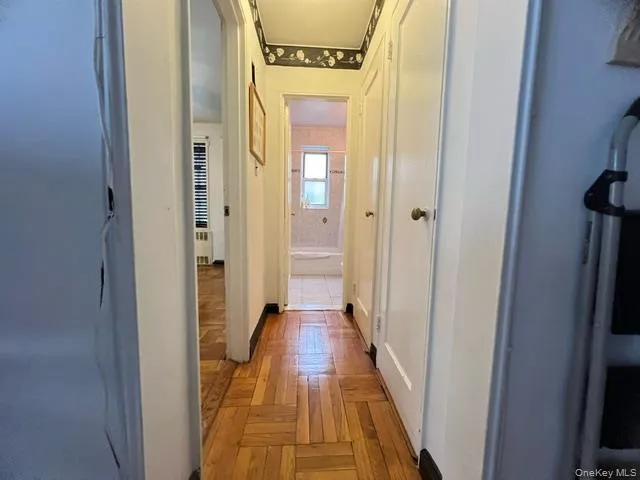 a view of a hallway with wooden floor and a bathroom