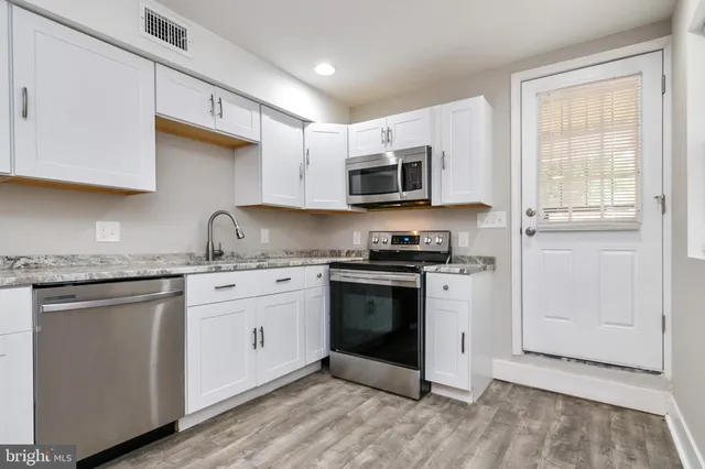 a kitchen with granite countertop white cabinets stainless steel appliances and a sink