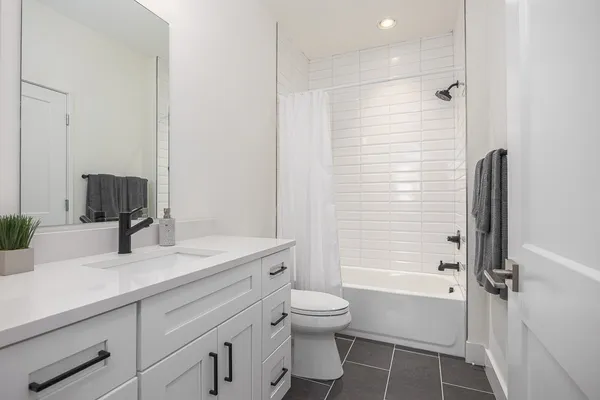 a bathroom with a granite countertop sink toilet a large mirror a shower and a bathtub
