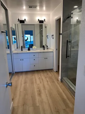 a bathroom with a granite countertop sink a mirror and shower