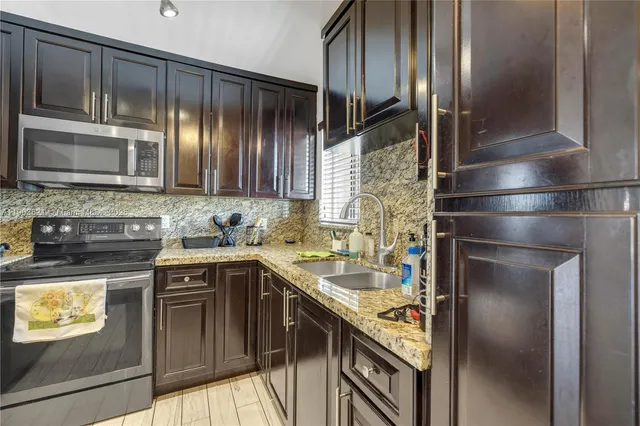 a kitchen with stainless steel appliances granite countertop a refrigerator a stove and a sink