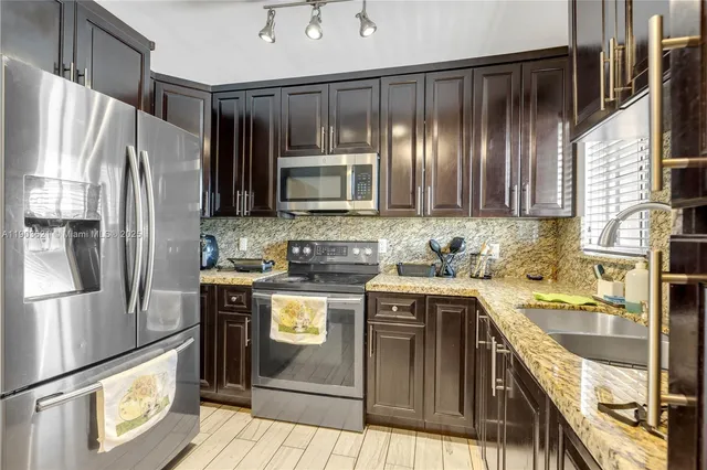 a kitchen with kitchen island granite countertop a sink stove and refrigerator