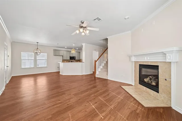 an empty room with wooden floor chandelier fan and windows
