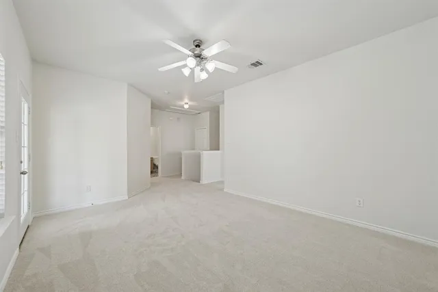 an empty room with a window and a ceiling fan